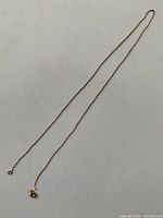 Full view of fine gold chain laid out showing length and clasp