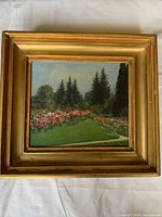 Framed oil painting showing full view of garden landscape with flowers and pine trees under a blue sky.