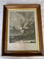 Framed antique engraving showing full view of the artwork featuring a stag near a fence in a natural setting, under wooden frame with gold inner lining and broken glass.