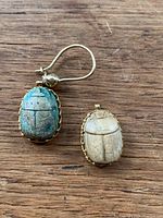 Top view showing the blue and beige scarab earrings, one with hook and one without.