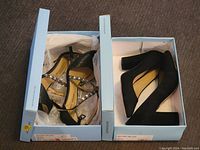 Two pairs of Antonio Melani women's shoes in their original shoe boxes. Left box contains rhinestone strap sandals; right box contains black suede block heels.