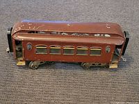 Side view of brown metal antique Lionel Pullman train car showing windows, couplers, and wheels.