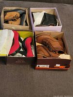 Four pairs of shoes and boots in boxes: black and tan Sporto boots, black ankle boots, red high-heeled shoes, and brown lace-up boots.