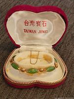Front view of vintage gold and green stone bracelet in red velvet Taiwan Jewel box.