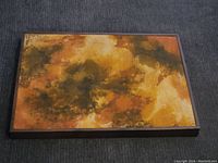 Full view of the abstract painting with warm tones in a wooden frame
