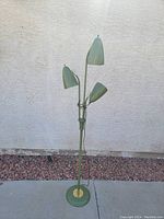 Full view of olive green metal floor lamp with three cone-shaped shades and brass accents.