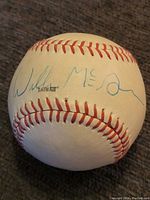 Signed baseball showing blue ink signature that reads 'Willie McCovey' or similar on white baseball with red stitching.