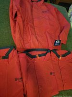 Four red Chevron branded work jackets laid flat showing fronts with logos, snap buttons, and collar trim.