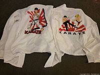 Photo showing two white karate uniforms with colorful vintage karate graphics on the back.