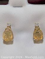 Close-up front view of the pair of 14K gold earrings with pear-shaped opal and diamonds.