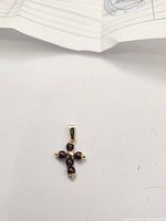 Photo of the gold garnet pendant on white background showing garnet stones and gold bale clearly, with part of certification document visible in background