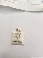 Close up photo of the 10k gold maple leaf pendant on a white padded display with '10 KT GOLD' text.