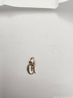 Small 10k gold initial 'G' pendant on a white background showing size and overall shape