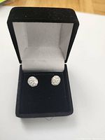 Pair of white gold stud earrings set with multiple small diamonds in a black velvet box