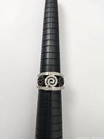 Front view of ring showing central swirl motif and black diamond pavé