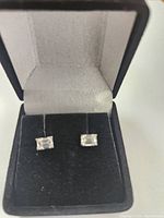 Front view of pair of emerald cut diamond stud earrings in black jewelry box