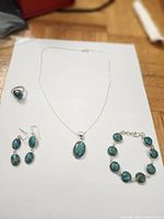 Full jewelry set displayed including ring, pendant necklace, earrings, and bracelet on white background.