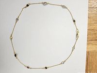 Full view of gold plated necklace with 11 colored simulated gemstones spaced evenly on fine chain.