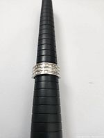 Front view of sterling silver ring with three rows of diamonds on a ring sizing tool showing size 7.