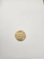 Detailed close-up photo showing the gold-colored metal coin with embossed pirate symbols and markings on a white background.