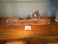 Front view of antique wooden hand planer showing length and handle design.