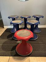 Front view of 3 large and 2 medium blue Hokki stools with 1 red small stool in front, showing overall set layout and shape