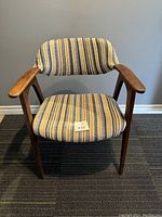 Front view of mid-century modern chair showing wooden arms and striped fabric seat and backrest.