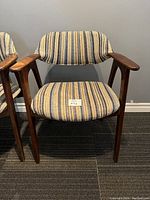Front view of one mid century modern side arm chair showing striped upholstery and wooden frame.