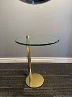 Full side view of the mid century modern side table showing the glass top and brass base.
