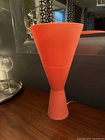 Orange silicone table lamp standing in its fully extended upright position on a wooden surface.