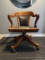 Front view of vintage oak and leather bankers chair showing wooden frame, leather seat and backrest.