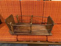 Photo of antique Indigenous wooden baby cradle showing entire item from a front angled perspective highlighting the base, vertical posts, and horizontal rails.