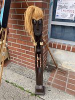 Full height shot showing whole wooden figure with hair, base, rope on arms, and facial features.