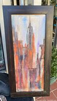 Framed original Eli St.John cityscape painting with muted blues, oranges, grays, and purples. Signed on lower left corner.