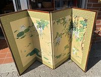 Full view of the four-panel folding screen showing floral and nature hand-painted scenes on a beige background with patterned border.