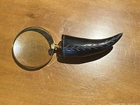 Magnifying glass resting on wooden surface showing full length and round lens