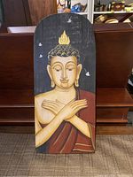 Full view of tall rectangular wooden plaque featuring Buddha figure with golden skin and rust-colored robe on a dark background with white birds.