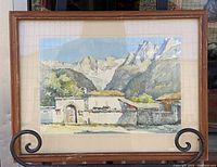 Full view of framed watercolour painting showing mountain range and building with archway, set in a wooden frame with visible damage.