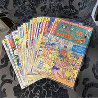 Stack of 18 Archie comic books fanned out on a fabric surface
