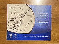 Blue keepsake case featuring a large coin design and bilingual text describing the Vancouver 2010 Circulation Coins set by RBC.