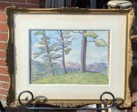 Full view of the framed watercolour painting showing landscape scene with three trees, grassy hill, and distant mountains under cloudy sky. The ornate gold frame shows some wear and damage.