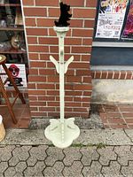 Front view of the entire wooden hanger stand showing the carved top, central vertical support, three outward hanger arms, and carved base.