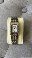 Single photo showing Kenneth Cole ladies watch with silver metal link band and rectangular face on cushion.