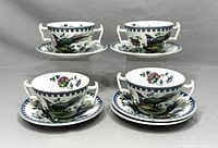 Four cups and five saucers arranged to show front designs including colorful birds and floral patterns.