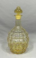 Full front view of amber-tinted bubble pattern glass decanter with stopper on top, straight neck and rounded body