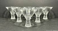 Front view of six vintage Nachtmann Broadway crystal martini glasses arranged in a line showing textured stems and clear bowls.