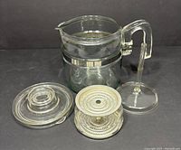 Complete Pyrex Flameware percolator coffee pot disassembled showing all parts: glass pot, lid, metal basket, and stem