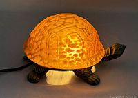 Illuminated turtle lamp on dark background, showing amber shell glowing