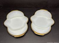 Front view of two vintage Fire King milk glass divided trays with gold beaded edge trim and small handles, placed side by side.