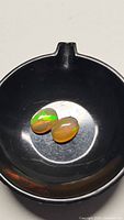 Two oval cabochon cut opal gemstones displayed inside a black container, showing bright rainbow color flashes under light.